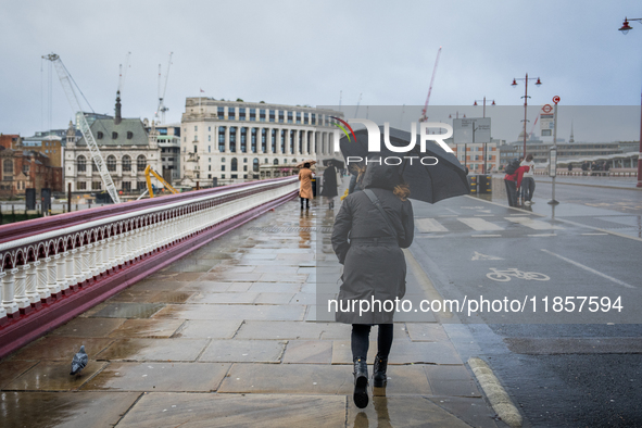 A woman holds an umbrella while walking across a wet bridge during Storm Darragh on December 8, 2024, in London, United Kingdom. London's Ro...