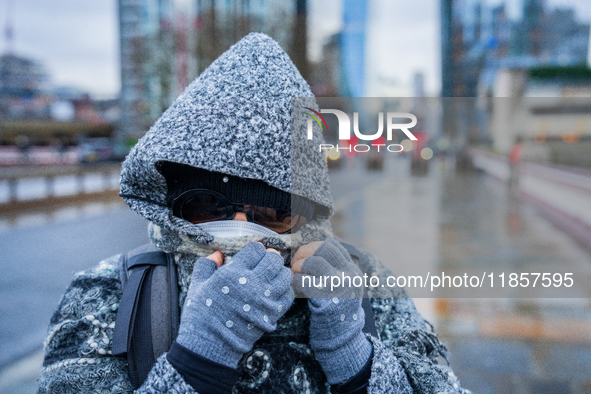 A woman with hood, scarf, and gloves braves the cold and rainy weather caused by Storm Darragh on December 8, 2024, in London, United Kingdo...