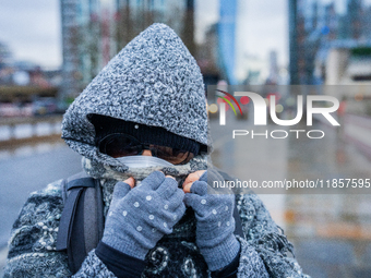 A woman with hood, scarf, and gloves braves the cold and rainy weather caused by Storm Darragh on December 8, 2024, in London, United Kingdo...