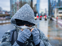 A woman with hood, scarf, and gloves braves the cold and rainy weather caused by Storm Darragh on December 8, 2024, in London, United Kingdo...