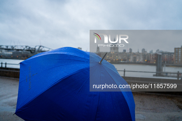 A blue umbrella provides cover during a rainy day with St. Paul's Cathedral in the background as Storm Darragh impacts London on December 8,...