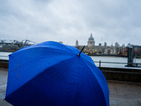 A blue umbrella provides cover during a rainy day with St. Paul's Cathedral in the background as Storm Darragh impacts London on December 8,...