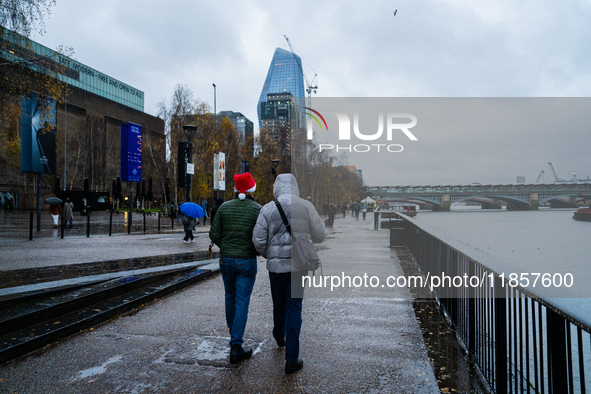 Two people walk along the Thames Riverbank during Storm Darragh, one wearing a Santa hat, on December 8, 2024, in London, United Kingdom. Lo...