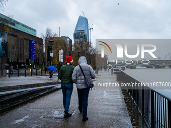 Two people walk along the Thames Riverbank during Storm Darragh, one wearing a Santa hat, on December 8, 2024, in London, United Kingdom. Lo...