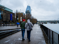 Two people walk along the Thames Riverbank during Storm Darragh, one wearing a Santa hat, on December 8, 2024, in London, United Kingdom. Lo...