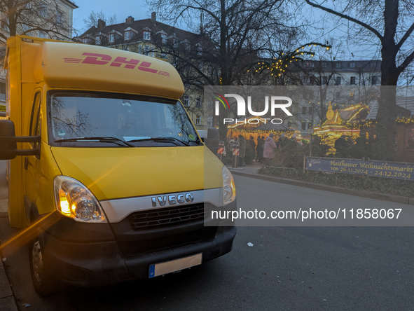 A yellow DHL delivery van parks near the Haidhauser Christmas Market in Munich, Bavaria, Germany, on December 11, 2024. The glowing lights o...