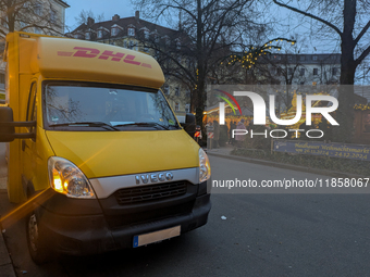 A yellow DHL delivery van parks near the Haidhauser Christmas Market in Munich, Bavaria, Germany, on December 11, 2024. The glowing lights o...