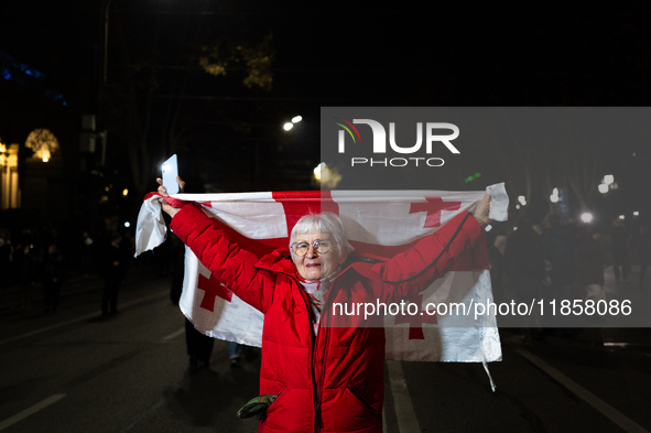 A Georgian pro-Europe demonstrator carries a Georgian flag during a protest against the Government's postponement of European Union accessio...