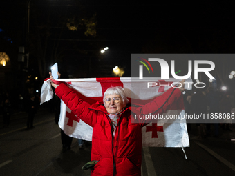 A Georgian pro-Europe demonstrator carries a Georgian flag during a protest against the Government's postponement of European Union accessio...