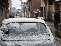 People walk while holding umbrellas during snowfall in Sopore, Jammu and Kashmir, India, on December 12, 2024. (