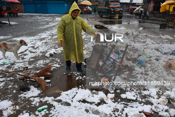 A municipal worker unloads a cart filled with garbage amid snowfall in Sopore, Jammu and Kashmir, India, on December 12, 2024. 