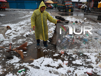 A municipal worker unloads a cart filled with garbage amid snowfall in Sopore, Jammu and Kashmir, India, on December 12, 2024. (