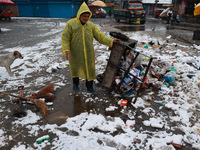 A municipal worker unloads a cart filled with garbage amid snowfall in Sopore, Jammu and Kashmir, India, on December 12, 2024. (