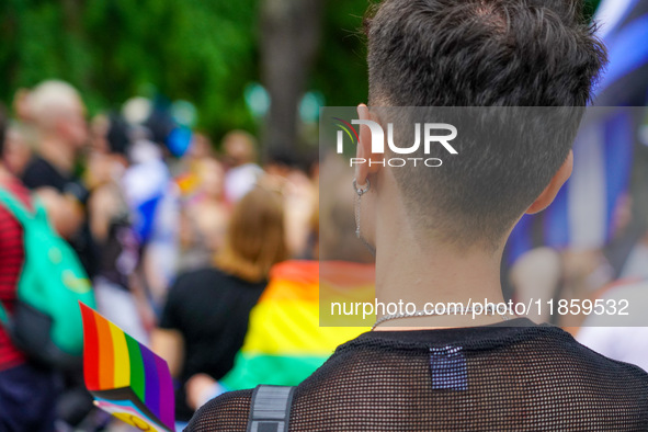 A young man stands at the Christopher Street Day (CSD) Parade in Mannheim, Germany, on August 12, 2023, displaying a rainbow flag and wearin...