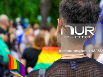 A young man stands at the Christopher Street Day (CSD) Parade in Mannheim, Germany, on August 12, 2023, displaying a rainbow flag and wearin...