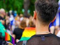 A young man stands at the Christopher Street Day (CSD) Parade in Mannheim, Germany, on August 12, 2023, displaying a rainbow flag and wearin...