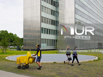 In Düsseldorf, Germany, on May 23, 2022, a Deutsche Post postman wearing the company’s signature yellow and black uniform delivers mail with...