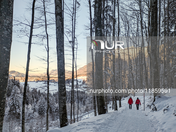 A man and a woman walk through the snowy landscape near Bavarian Oberstdorf in Bavaria, Swabia, Oberallgau, Germany, on January 20, 2024, du...