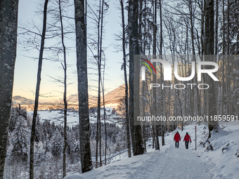 A man and a woman walk through the snowy landscape near Bavarian Oberstdorf in Bavaria, Swabia, Oberallgau, Germany, on January 20, 2024, du...