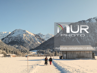 A family walks through the snowy landscape near Bavarian Oberstdorf in Bavaria, Swabia, Oberallgau, Germany, on January 20, 2024. Oberstdorf...