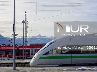 On November 24, 2024, in Garmisch-Partenkirchen, Bavaria, Germany, an ICE train with its sleek design stands next to a vibrant red Regional...