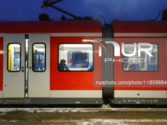 Passengers are inside a red Deutsche Bahn S-Bahn train at the Gauting suburban station in Bavaria, Germany, on November 22, 2024.(