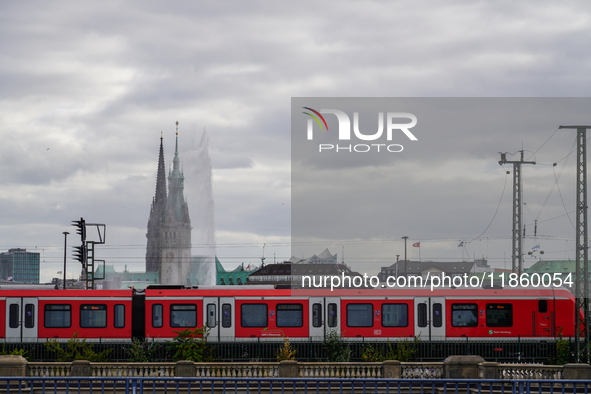 A red S-Bahn Hamburg train traverses a rail line with the city’s iconic skyline in the background in Hamburg, Germany, on August 28, 2022.  