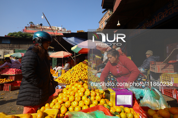 People purchase oranges from a local market in Kathmandu, Nepal, on December 12, 2024. Nepali fruit markets are flooded with oranges as the...