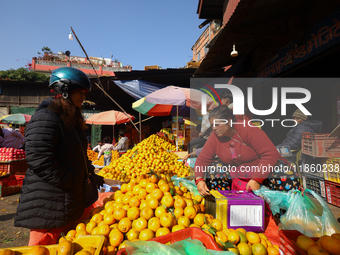 People purchase oranges from a local market in Kathmandu, Nepal, on December 12, 2024. Nepali fruit markets are flooded with oranges as the...