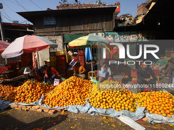 Nepali vendors wait for customers at a local market in Kathmandu, Nepal, on December 12, 2024. Nepali fruit markets are flooded with oranges...