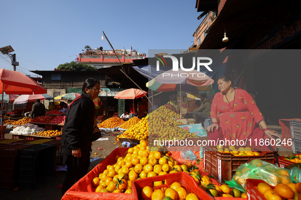 People purchase oranges from a local market in Kathmandu, Nepal, on December 12, 2024. Nepali fruit markets are flooded with oranges as the...