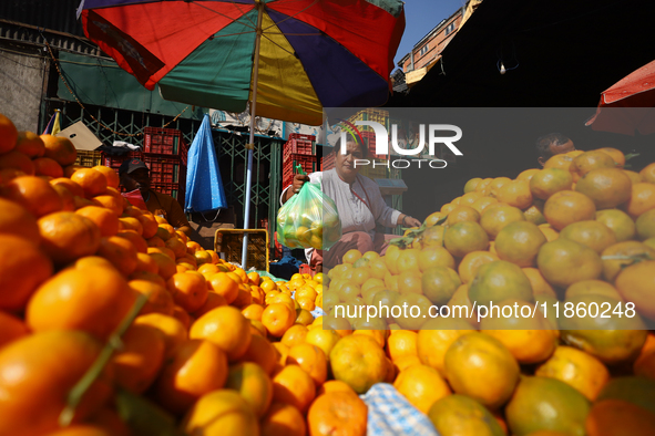 A Nepali vendor weighs and packs oranges at a local market in Kathmandu, Nepal, on December 12, 2024. Nepali fruit markets are flooded with...