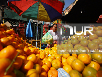 A Nepali vendor weighs and packs oranges at a local market in Kathmandu, Nepal, on December 12, 2024. Nepali fruit markets are flooded with...