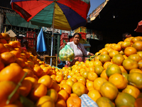 A Nepali vendor weighs and packs oranges at a local market in Kathmandu, Nepal, on December 12, 2024. Nepali fruit markets are flooded with...