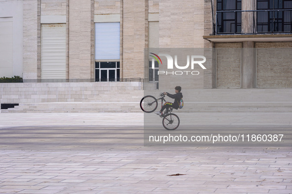 A boy cycles on a forecourt of a modern building in Lido, Venice Lagoon, Italy, on November 13, 2021. 