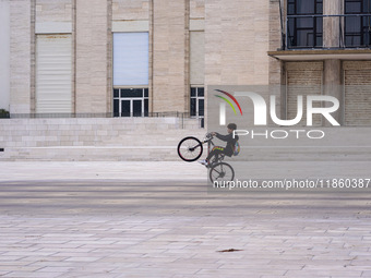 A boy cycles on a forecourt of a modern building in Lido, Venice Lagoon, Italy, on November 13, 2021. (