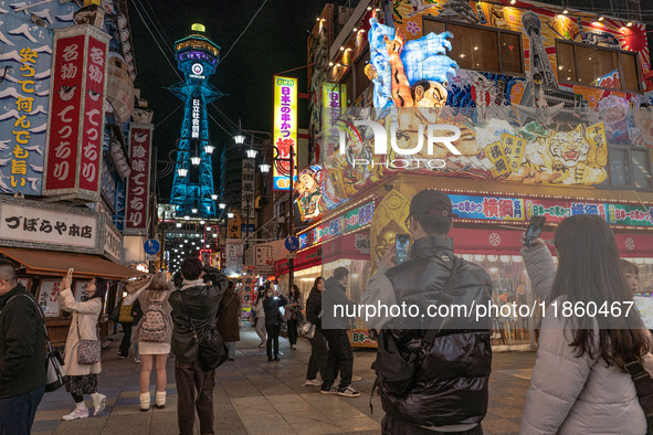 Tourists take photos in Shinsekai with Tsutenkaku tower in sight in Osaka, Japan, on December 12, 2024. Shinsekai, which means 'New World' i...