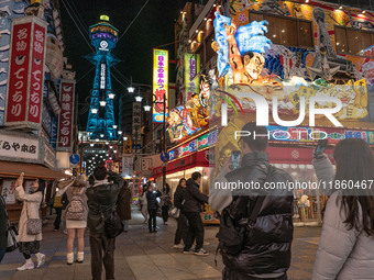 Tourists take photos in Shinsekai with Tsutenkaku tower in sight in Osaka, Japan, on December 12, 2024. Shinsekai, which means 'New World' i...