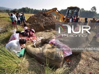 Women pray next to the carcass of a female elephant, who according to forest officials, dies of ill health in a paddy field, for its burial...