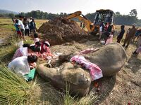 Women pray next to the carcass of a female elephant, who according to forest officials, dies of ill health in a paddy field, for its burial...