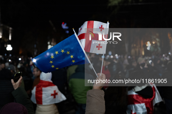 Anti-government protesters wave a Georgian and European Union flag during a demonstration against the Georgian government's postponement of...