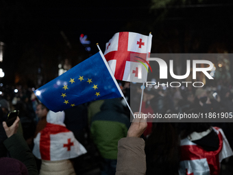 Anti-government protesters wave a Georgian and European Union flag during a demonstration against the Georgian government's postponement of...