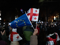 Anti-government protesters wave a Georgian and European Union flag during a demonstration against the Georgian government's postponement of...