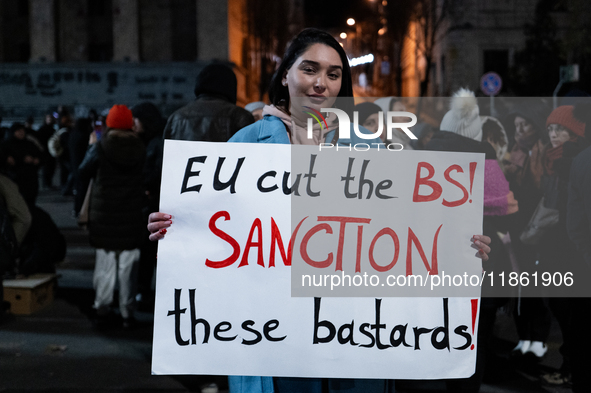 An anti-government protester carries a sign that reads ''EU cut the BS, sanction these bastards'' during a demonstration against the Georgia...