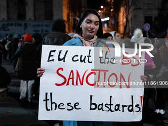 An anti-government protester carries a sign that reads ''EU cut the BS, sanction these bastards'' during a demonstration against the Georgia...