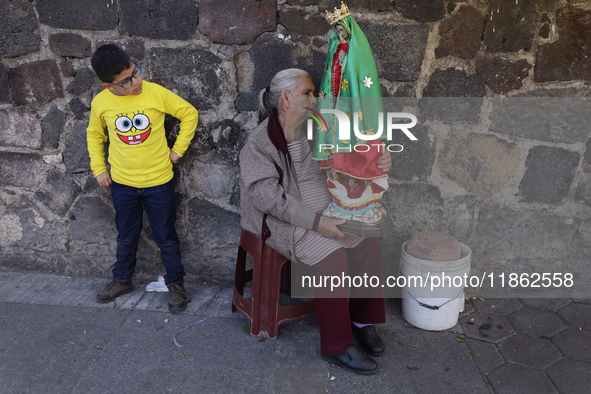 A resident of Santa Maria Tomatlan in the Iztapalapa municipality, Mexico City, carries an image for the celebration of the Day of the Virgi...