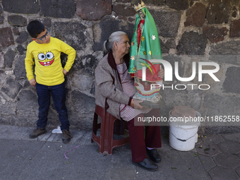 A resident of Santa Maria Tomatlan in the Iztapalapa municipality, Mexico City, carries an image for the celebration of the Day of the Virgi...