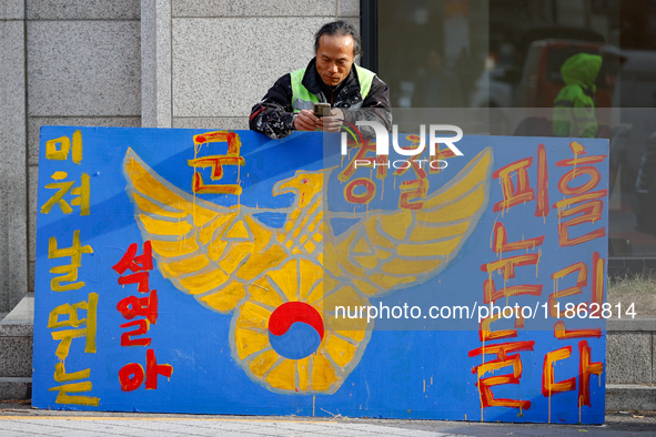 A protester leans against a hand-painted sign in front of the People Power Party's central headquarters in Yeouido, Seoul, South Korea, on D...