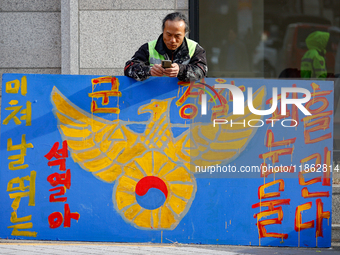 A protester leans against a hand-painted sign in front of the People Power Party's central headquarters in Yeouido, Seoul, South Korea, on D...