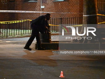 The NYPD evidence collection team gathers evidence and marks shell casings at the scene where two people are shot at Lafayette Gardens NYCHA...